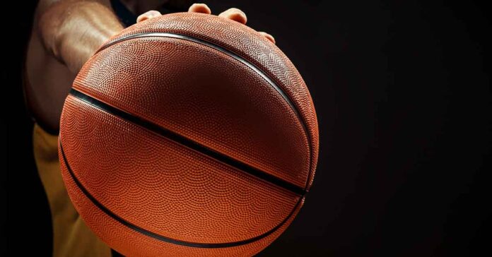 Silhouette view of a basketball player holding basket ball on black background